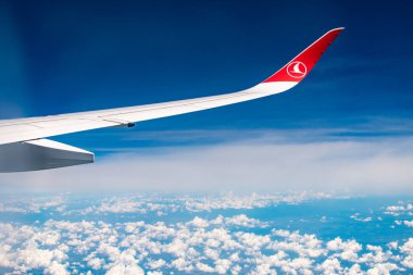 Türk havayollarının amblemiyle uçağın kanadının altında bulutlar ve mavi gökyüzü,