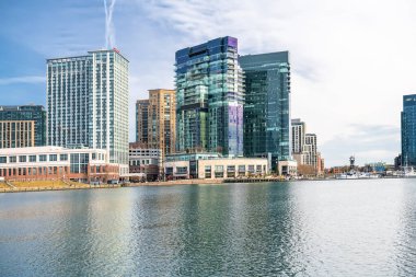 Baltimore 'un İç Limanı. Mavi gökyüzünün altındaki kıyı şeridi gökdelenleri suya yansıyor..