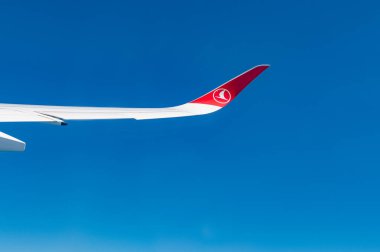 Türk hava yollarının amblemi olan uçağın kanadının altında açık mavi gökyüzü, metin için yer.