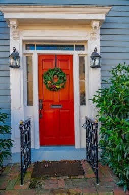 Bir evin kırmızı ön kapısında Noel çelengi.