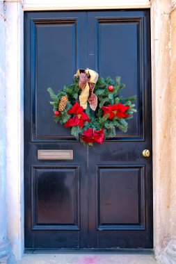 Geleneksel Noel çelengi eski bir evin ön siyah ahşap kapısında..