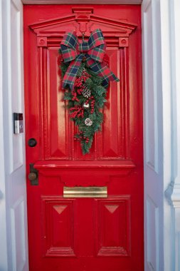 Bir evin kırmızı ön kapısında Noel çelengi.