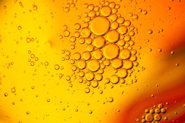 Parlak turuncu arka planda yüzen yağ kabarcıkları. 