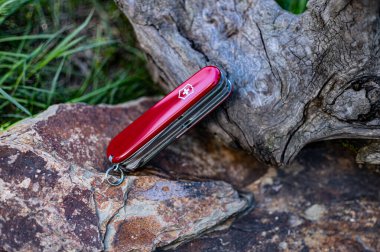 Kırmızı Victorinox, İsviçre çakılarını kapalı bıçaklarla katlayan klasik cep cebi bir taşın üzerinde duruyor..