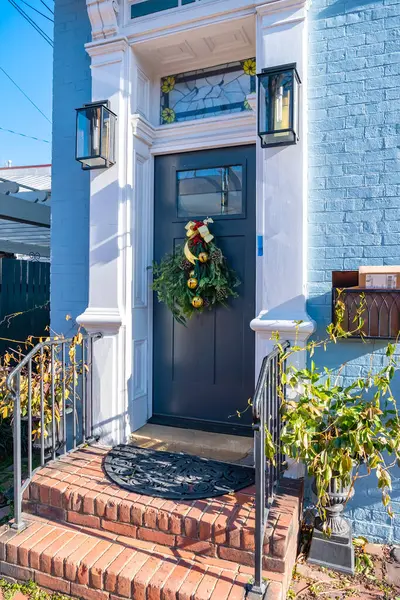 Güzel, eski, ahşap bir kapıda çam dallarıyla süslenmiş zarif bir Noel çelengi.