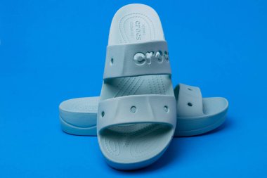 Mavi arka planda kendine özgü bir tasarımı olan mavi Crocs sandaletleri.