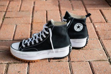 Bir çift siyah Converse ayakkabısı kaldırımda duruyor..