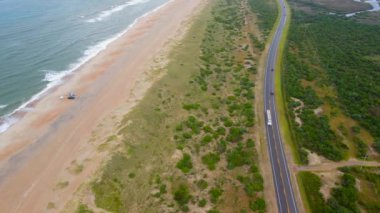 Kuzey Carolina 'nın dış kıyıları. Kuzey Carolina 'da okyanus kıyısı boyunca uzanan bir yol. Sarı kum, okyanus, otoyoldaki arabalar. Drone görünümü