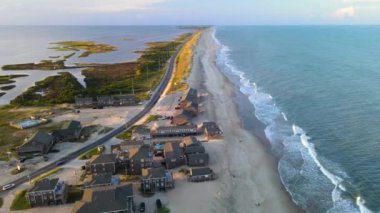 Kuzey Carolina 'da okyanus kıyısı boyunca uzanan bir yol. Sarı kum, okyanus, yeşil çimenler, otoyoldaki arabalar. Drone fotoğrafçılığı