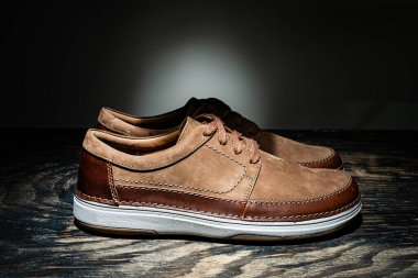 Koyu ahşap zeminde bir çift erkek süet ayakkabısı..