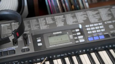 Ses sisteminin yanındaki Casio piyanosundaki Sony kulaklıkları. Kamera piyanonun etrafında hareket eder..