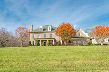 Büyük kır eviyle sonbahar manzarası. Altın yapraklar ve mavi gökyüzü.