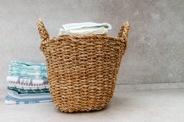 Temiz havlularla dolu bir sepet ve masanın üzerinde bir yığın mutfak havlusu. Boşluğu kopyala.