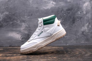 Gri duvarda beyaz Reebok yüksek spor ayakkabıları.