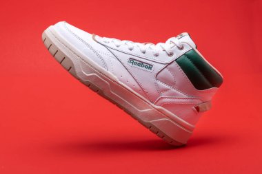 White reebok athletic sneakers on red background. clipart