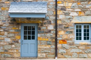 Taş bir evin giriş kapısı. Sokağın karşısındaki eve giriş. Taş duvardaki pencereler.