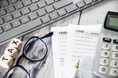 1040 numaralı vergi formunu dolduruyorum. Hesap makinesi, bozuk para, gözlük, form ve kalem masanda. Devlet vergileri ve vergi beyannamelerinizin hesaplanması.