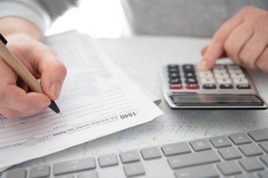 Vergi ödeme zamanı. Finansal hesaplamalar yapmak veya vergi iadesi yapmak için hesap makinesi ve bilgisayar klavyesi.