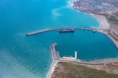 Denizde körfezin manzarası ve körfezde yükleme altında duran bir tanker. İnsansız hava aracının yüksekliğinden bak.