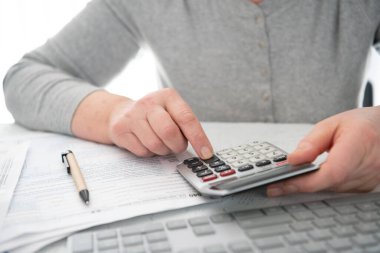 Vergi ödeme zamanı. Finansal hesaplamalar yapmak veya vergi iadesi yapmak için hesap makinesi ve bilgisayar klavyesi.