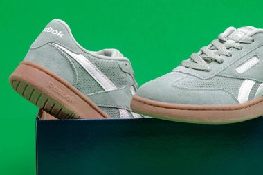 Yeşil arka planda spor ayakkabıları Reebok ve kutu.