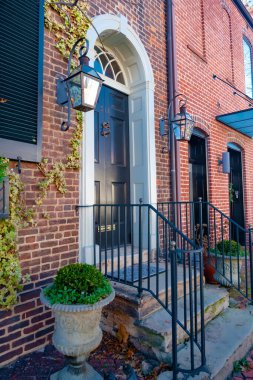 Çekici tuğlalı eski bir ev, merdivenleri ve parmaklıkları olan ahşap bir kapı..