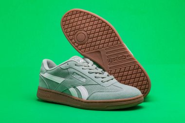 Yeşil arka planda rahat Reebok ayakkabıları. Reebok küresel bir spor ayakkabısı üreticisi..