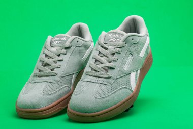 Yeşil arka planda yürümek ve koşmak için Reebok hafif spor ayakkabıları.