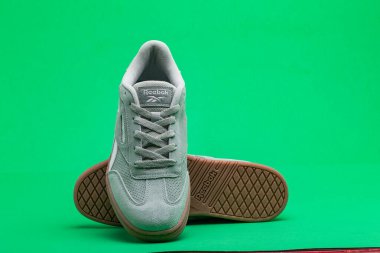 Yeşil arka planda rahat Reebok ayakkabıları. Reebok küresel bir spor ayakkabısı üreticisi..