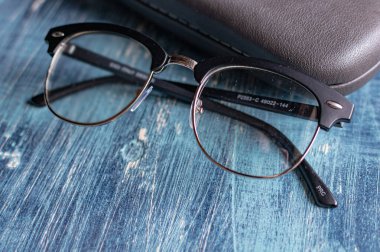 Mavi bir masada, diyopterli ve gri gözlüklü optik gözlük.