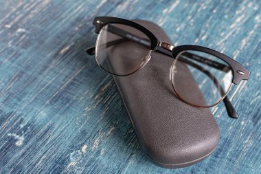 Bir çift siyah çerçeveli optik gözlük ve gri bir gözlük. 