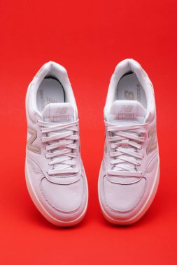 Kırmızı arka planda beyaz, dengeli bir çift spor ayakkabı. Spor ayakkabı konsepti