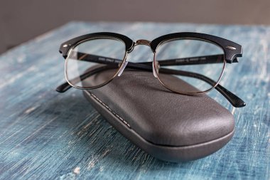 Bir çift siyah çerçeveli optik gözlük ve gri bir gözlük. 