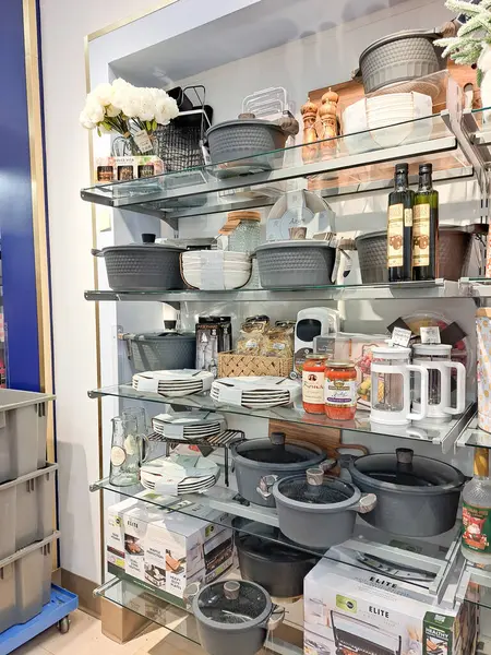 Mutfak malzemeleriyle büyük bir süpermarkette sergileniyor. Tavalar ve tencereler tezgahın üzerinde..