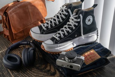 Converse spor ayakkabıları, Levi 'nin kotu, kulaklıklar ve tahta bir masada bir çanta..