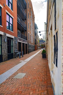 Mavi gökyüzünün altındaki tuğla duvarlar arasında kırmızı tuğladan kaldırım.