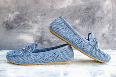 Mavi yumuşak kumaş kadın ayakkabıları. Gri bir arka planı var..