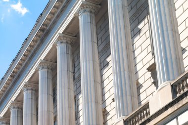 Binanın ön cephesinde simetrik beyaz anıtsal sütunlar.