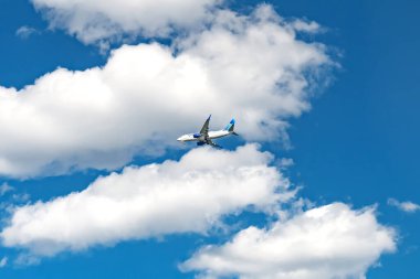 Gökyüzünde yolcu uçağı, aşağıdan görüş. Arkasında bulutlar olan United Airlines.