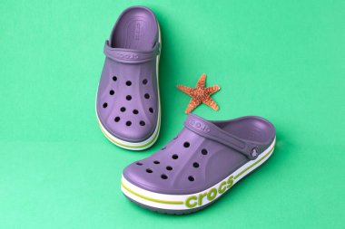 Yeşil arka planda gri timsah sandaletleri ve deniz yıldızları.