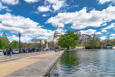 Washington 'daki Birleşik Devletler Kongre Binası. Capitol, bulutlu mavi gökyüzünün altında yeşil ağaçlarla çevrilidir..