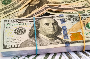 Arkasında dolar olan, lastik bantla bağlanmış yüz dolarlık banknotlar yığını..