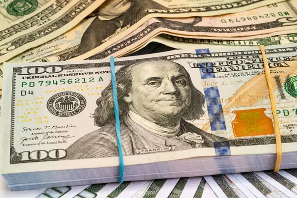Arkasında dolar olan, lastik bantla bağlanmış yüz dolarlık banknotlar yığını..