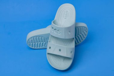 Açık mavi arka planda bir çift kadın mavi Crocs sandaleti.