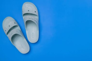 Açık mavi arka planda bir çift kadın mavi Crocs sandaleti. Üst Manzara. Metin için boşluk.
