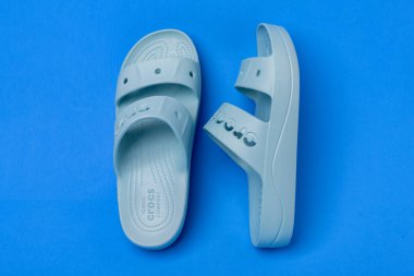 Mavi arka planda imzası olan bir çift mavi Crocs sandaleti..