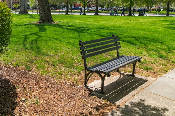 Kaldırımın kenarındaki şehir parkında ahşap bir bank..