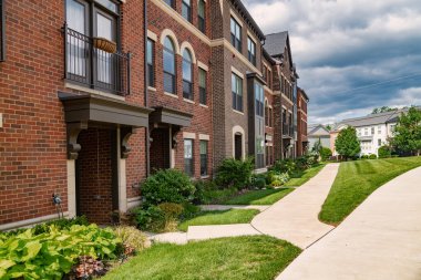 Yeşil çimenli tuğla apartman ve duvar boyunca uzun kaldırım..