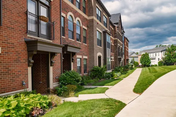 Yeşil çimenli tuğla apartman ve duvar boyunca uzun kaldırım..