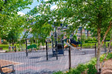 Parlak renkli oyun ekipmanları, eskrim ve peyzaj ile çocuk dostu oyun alanı.